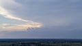 Dramatic sky view during sunset, featuring varying hues of blue and orange. The landscape below shows fields and a dista Royalty Free Stock Photo