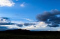 Dramatic skyscape over silhouette of mountains and flatland with stormclouds forming in very blue sky near dusk Royalty Free Stock Photo