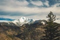 Dramatic snowy peak lonely mountain Norway landscape and pine tree foreground scenic view with moody cloudy sky background winter Royalty Free Stock Photo