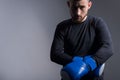 Dramatic sports portrait of a handsome bearded brutal guy in sportswear, standing in combat pose, taking off boxing gloves. On a