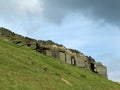 A dramatic stone outcrop on a steep green hillside in yorkshire moors landscape with the remains of an old dry stone wall Royalty Free Stock Photo