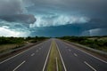 Dramatic storm clouds loom ominously over the empty highway