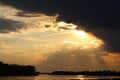 Dramatic storm clouds over the Vistula River at sunset, sun rays breaking through dark sky and reflecting on water Royalty Free Stock Photo