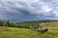 Dramatic storm sky with dark clouds over green meadows and forested hills. Royalty Free Stock Photo