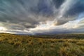 Dramatic storm sky landscape with sun rays between the clouds and over the mountains. Dark landscape Royalty Free Stock Photo