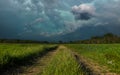 Dramatic stormy sky over a green field and dirt road Royalty Free Stock Photo