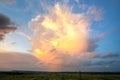 Dramatic stormy sunset over rural area with puffy clouds lit by orange setting sun and blue sky Royalty Free Stock Photo