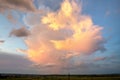 Dramatic stormy sunset over rural area with puffy clouds lit by orange setting sun and blue sky Royalty Free Stock Photo