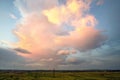 Dramatic stormy sunset over rural area with puffy clouds lit by orange setting sun and blue sky Royalty Free Stock Photo