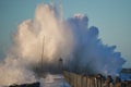 Dramatic, strong waves and foam spray hit the pier in Vorupoer on the North Sea coast of Denmark