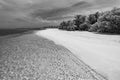 Artistic black and white beach scene. Dramatic island shore landscape, dark sky with calm water. Monochrome