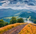 Dramatic summer scenery. Foggy summer scene of Krasna range with old country road.