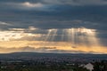 Dramatic sun ray through low clouds over city at sunset. The sun cuts through the clouds over the city. Sunbeams on the city Royalty Free Stock Photo