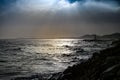 Dramatic sun rays through a cloudy dark sky over the sea Royalty Free Stock Photo