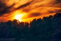 Dramatic sunset - bright red sky with clouds and the silhouette of a forest in the background, beautiful wild nature, landscape Royalty Free Stock Photo