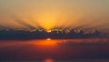 Dramatic sunset is depicted with the sun partially hidden behind a line of dark Royalty Free Stock Photo