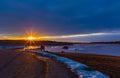 Catching the tail end of winter snow with ice fishing at Golden sunset and blue clouds reflecting on frozen lake. Royalty Free Stock Photo