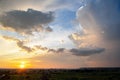 Dramatic sunset landscape of rural area with stormy puffy clouds lit by orange setting sun and blue sky Royalty Free Stock Photo