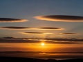 Dramatic sunset with lenticular clouds over a distant horizon Royalty Free Stock Photo