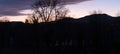 Dramatic sunset with lilac orange clouds over bar trees and hills in wintertime in Switzerland. Unprocessed and original Royalty Free Stock Photo