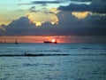 Dramatic Sunset over a cargo boat below the clouds and reflecting on the Pacific ocean Royalty Free Stock Photo