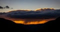 Dramatic Sunset Over Dark Mountain Silhouette with Golden Cloud Layer and Rainfall Royalty Free Stock Photo