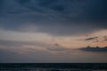 Dramatic sunset over ocean with dark clouds and calm water surface Royalty Free Stock Photo