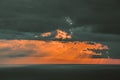Dramatic sunset over the ocean with orange and dark clouds casting rays of light on the water. Royalty Free Stock Photo