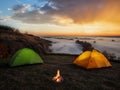 Dramatic sunset over the river and tents with a fire Royalty Free Stock Photo