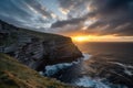 dramatic sunset over a rugged coastal cliff, with the sun peeking out from behind the clouds Royalty Free Stock Photo