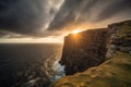 dramatic sunset over a rugged coastal cliff, with the sun peeking out from behind the clouds Royalty Free Stock Photo