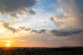 Dramatic sunset over rural area with stormy clouds lit by orange setting sun and blue sky Royalty Free Stock Photo