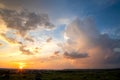 Dramatic sunset over rural area with stormy clouds lit by orange setting sun and blue sky Royalty Free Stock Photo