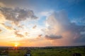 Dramatic sunset over rural area with stormy clouds lit by orange setting sun and blue sky Royalty Free Stock Photo