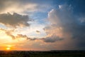 Dramatic sunset over rural area with stormy puffy clouds lit by orange setting sun and blue sky Royalty Free Stock Photo