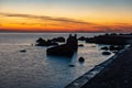 dramatic sunset over sea beach with rocks and stormy water Royalty Free Stock Photo