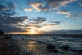 dramatic sunset over sea beach with rocks and stormy water Royalty Free Stock Photo