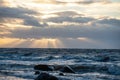 dramatic sunset over sea beach with rocks and stormy water Royalty Free Stock Photo