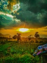Dramatic sunset over terraced farmland with lush green crops, dark clouds, and rays of light piercing through.& x22; Royalty Free Stock Photo