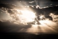 Dramatic sunset rays through a cloudy dark sky over the ocean Royalty Free Stock Photo