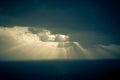 Dramatic sunset rays through a cloudy dark sky over the ocean Royalty Free Stock Photo