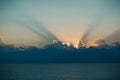 Dramatic sunset rays through cloudy dark sky over the ocean Royalty Free Stock Photo