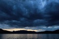 storm clouds over the ocean at sunset with a lighthouse in the distance