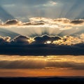 A dramatic sunset scene featuring sun rays streaming through scattered clouds, Royalty Free Stock Photo