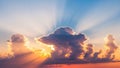 Dramatic sunset sky with crepuscular rays beaming through dark clouds casting warm orange and yellow light Royalty Free Stock Photo