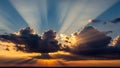 Dramatic sunset sky with crepuscular rays beaming through dark clouds and illuminating the horizon Royalty Free Stock Photo