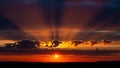 Dramatic Sunset Sky with Radiant Sun Rays Breaking Through Dark Clouds and Silhouetted Horizon Line Royalty Free Stock Photo
