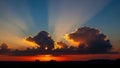Dramatic Sunset Sky with Sun Rays Bursting Through Dark Clouds Over Silhouetted Landscape Royalty Free Stock Photo
