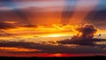 Dramatic sunset sky with vibrant orange and yellow crepuscular rays piercing through dark clouds Keywords: sunset Royalty Free Stock Photo