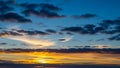 Dramatic sunset sky with vibrant orange and yellow hues illuminating dark clouds and wispy cirrus formations Royalty Free Stock Photo